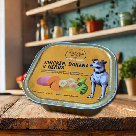 Dog food container labeled 'Chicken, Banana & Herbs' by Betty & Butch on a wooden surface.