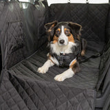 Dog sitting on a black quilted car bench cover