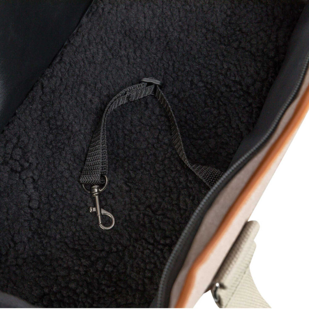Close-up of a pet carrier with a strap and metal clasp.