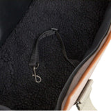 Close-up of a pet carrier with a strap and metal clasp.